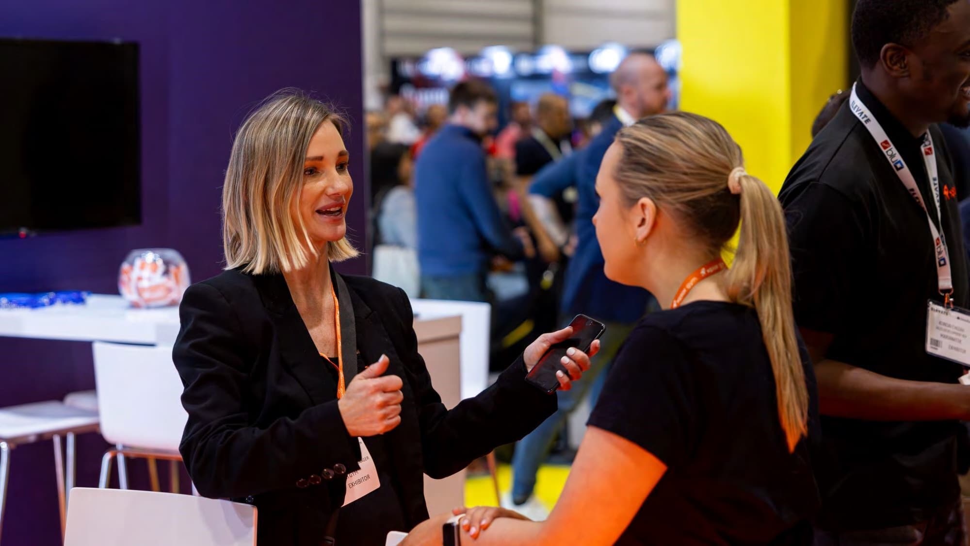 A researcher recording a spoken interview with an exhibitor on a conference floor